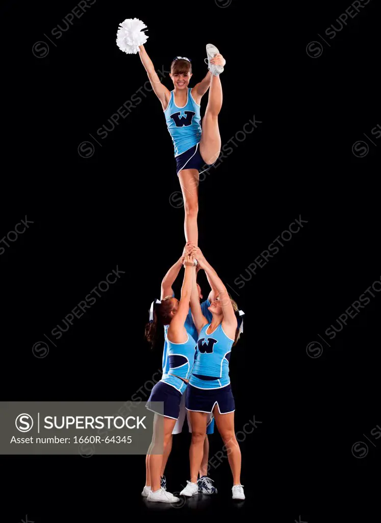 Studio shot of cheerleaders (16-17) supporting friend standing on one leg