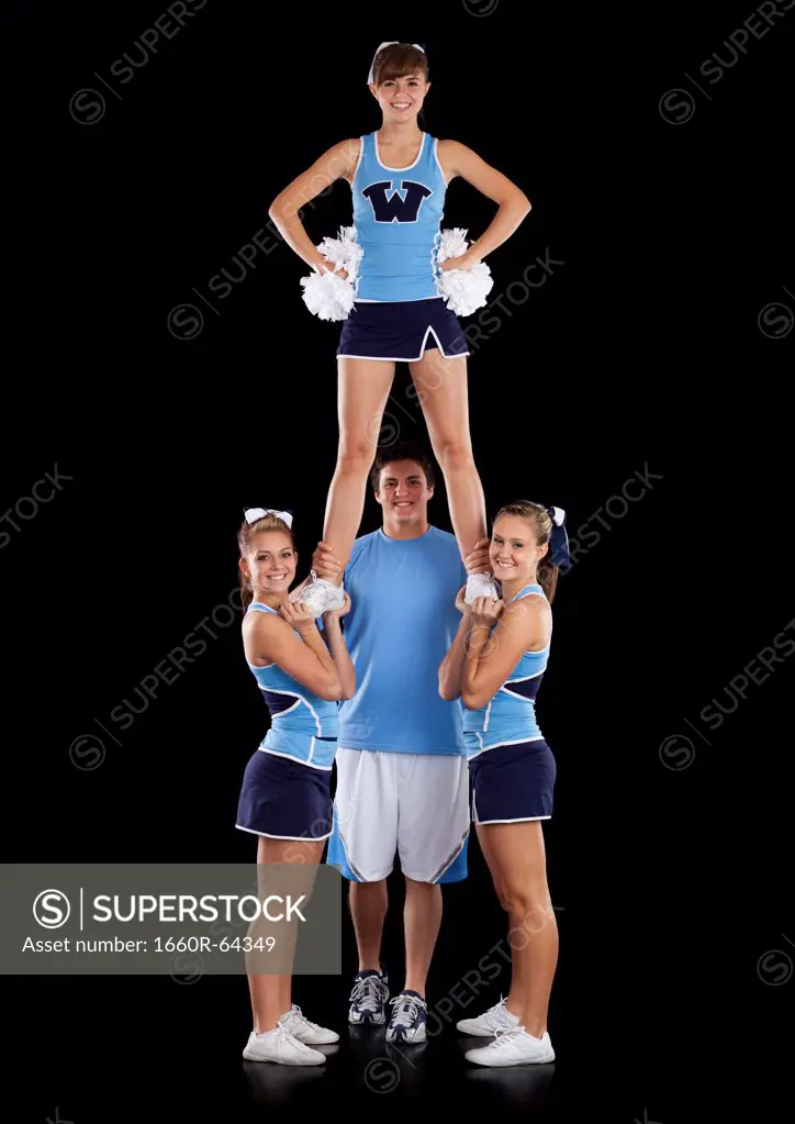 Studio shot of cheerleaders (16-17) assisting friend during performance