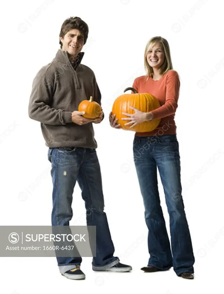 Portrait of a young couple holding pumpkins