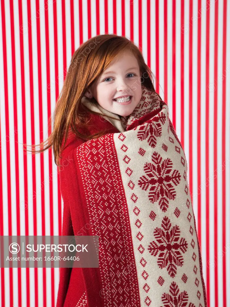 Studio portrait of girl (4-5) wrapped in red blanket
