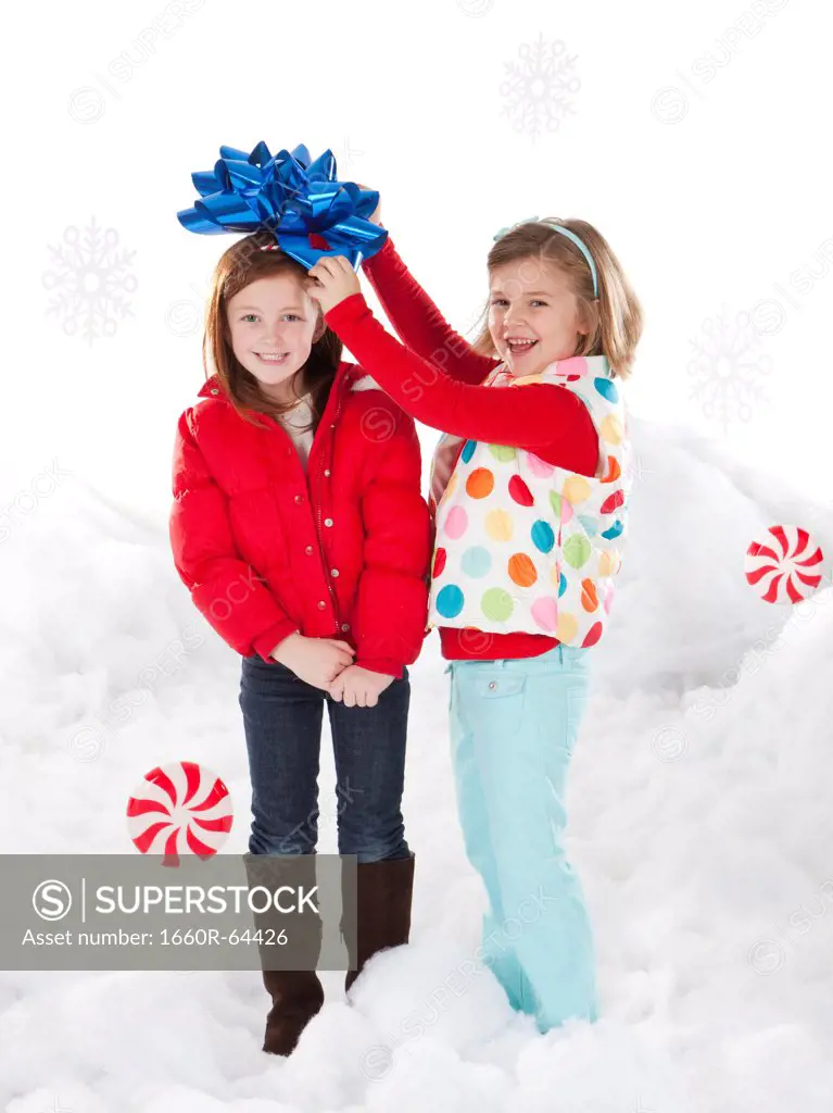 Studio portrait of girls (4-5, 6-7) standing in snow
