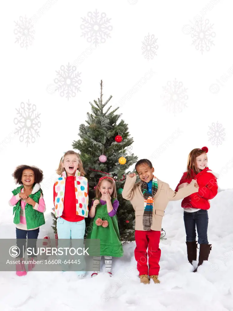 Group of kids (18-23months, 4-5,6-7) standing next to christmas tree