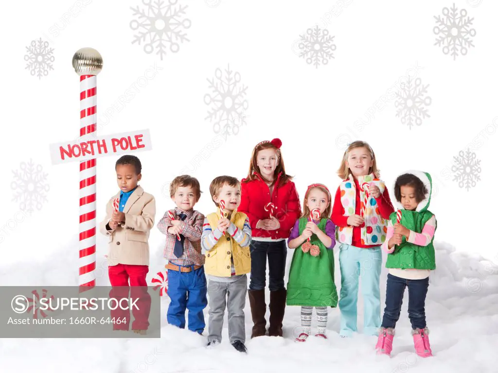Group of kids (18-23months, 2-3, 4-5, 6-7) standing next to North Pole sign