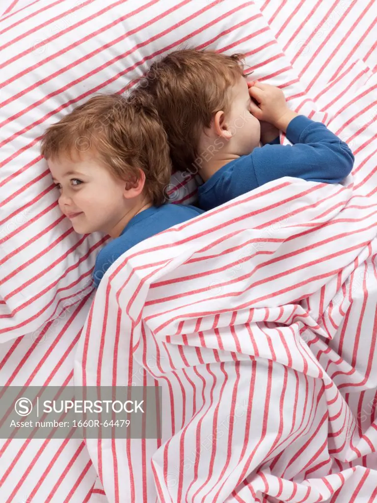 USA, Utah, Orem, Twin boys (2-3) wearing pajamas lying on bed