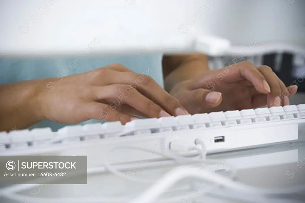 Close-up of a person's hands typing on a computer keyboard