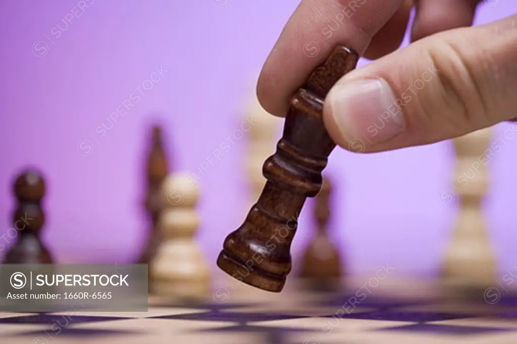 Close-up of a person's hand holding a chess piece