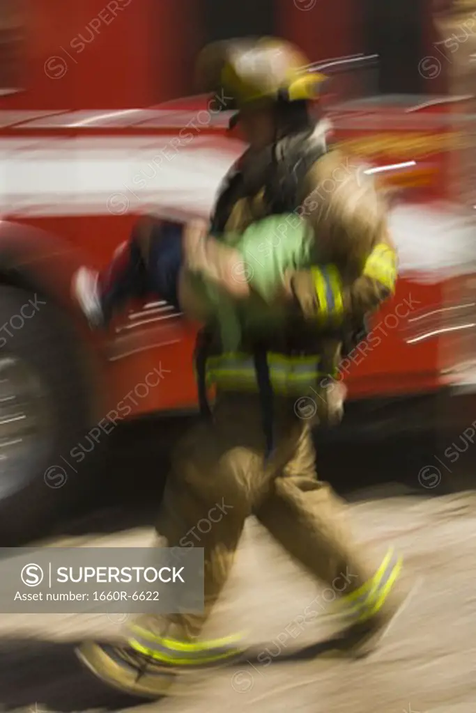 Profile of a firefighter carrying a wounded boy