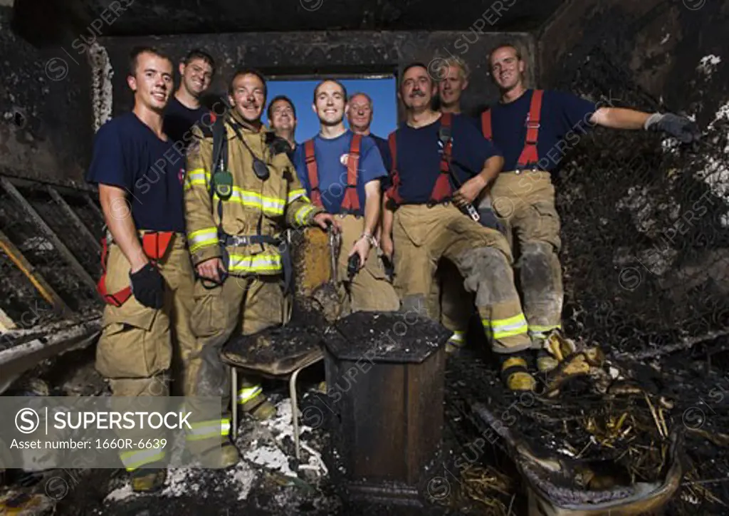 Low angle view of a group of firefighters posing in a damaged room