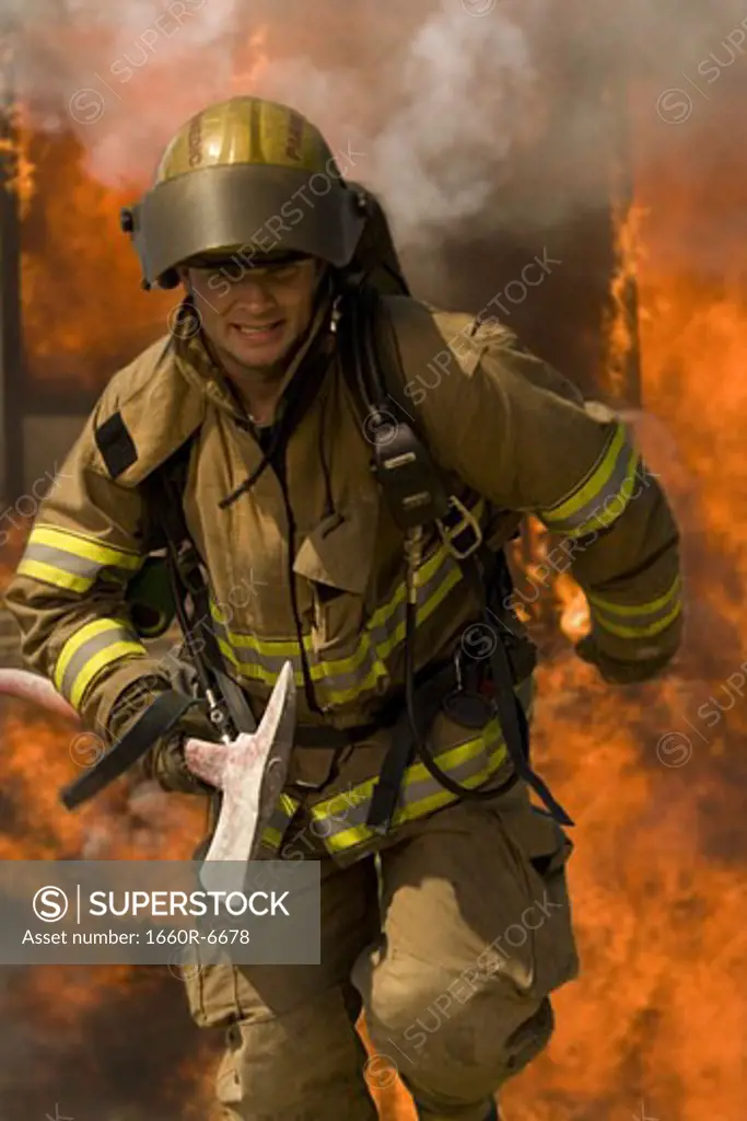 Firefighter running through fire holding an axe
