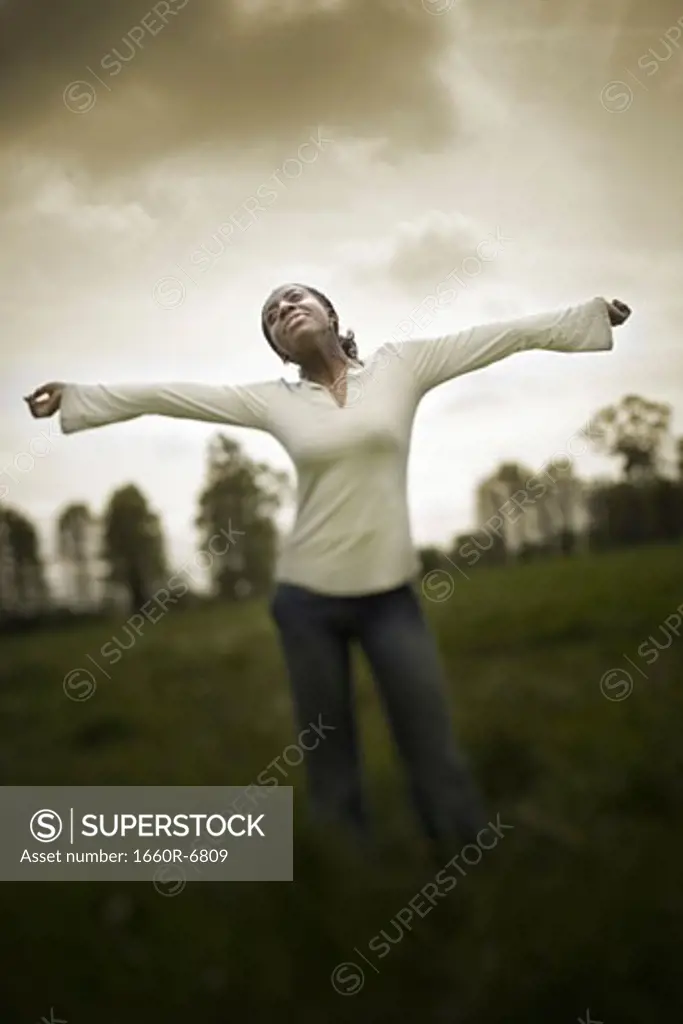 Teenage girl standing in a field with her arms outstretched
