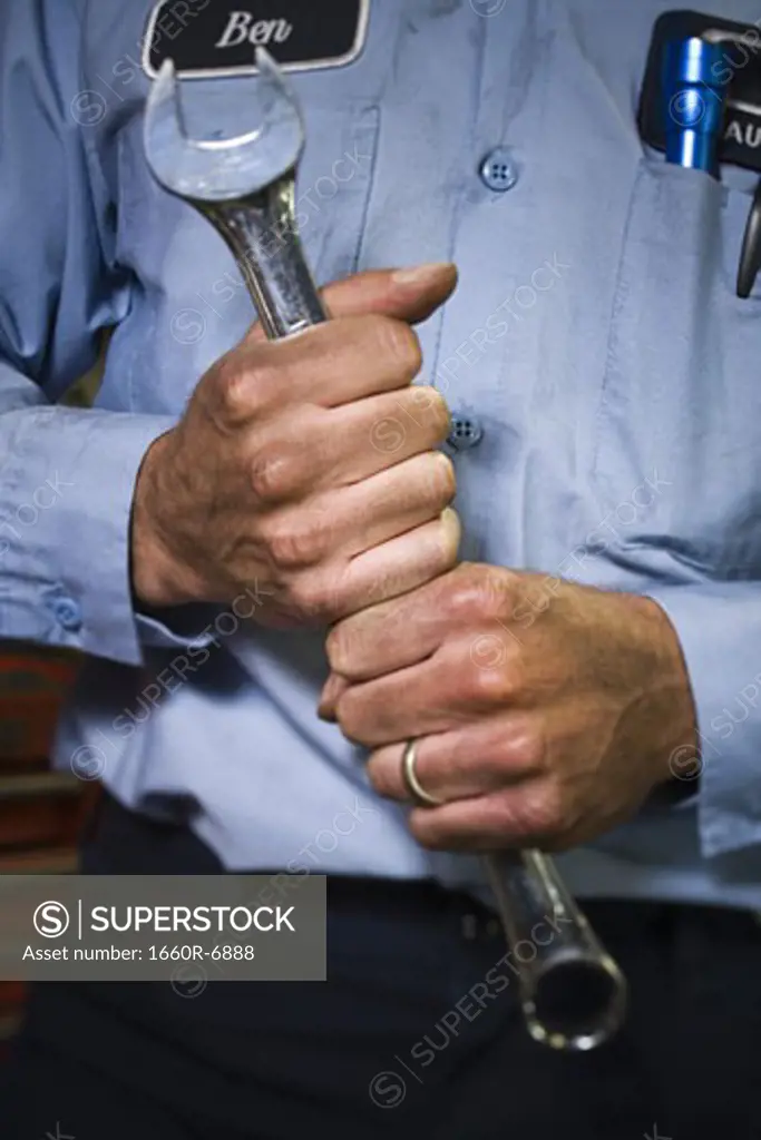 Mid section view of an auto mechanic holding a spanner