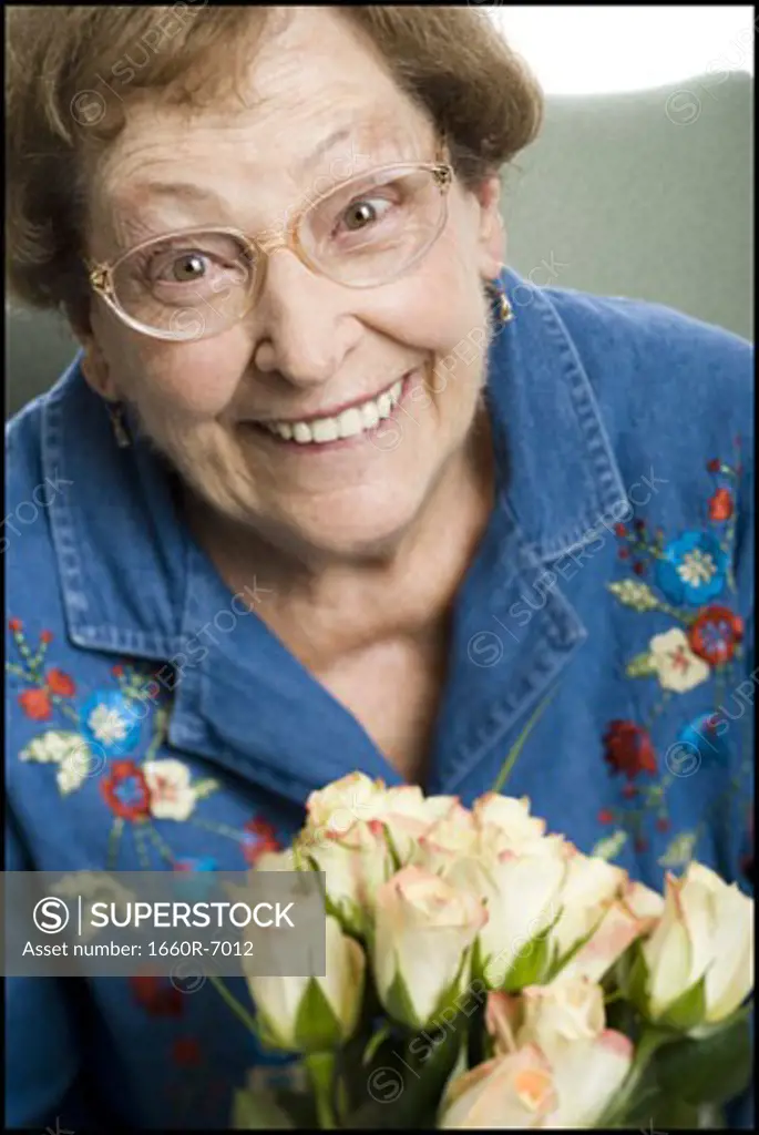 Portrait of a senior woman holding a bunch of white rose and smiling