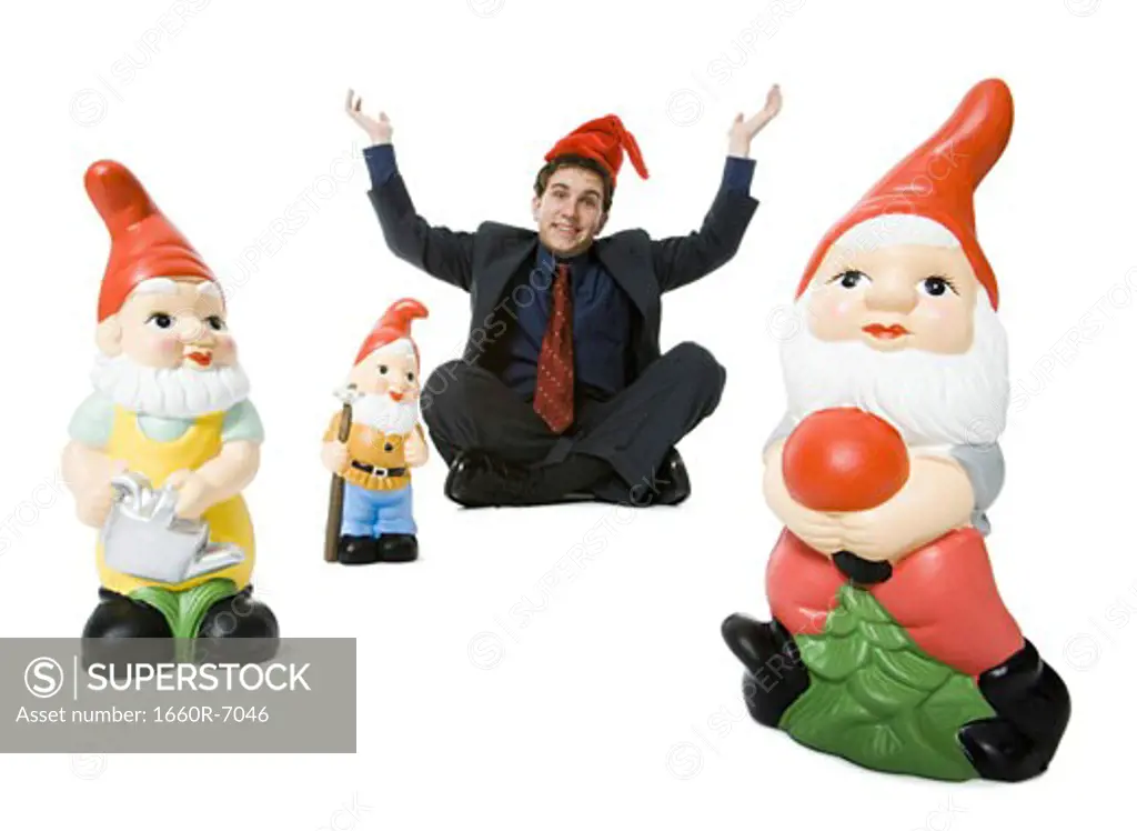 Portrait of a businessman sitting with three garden gnomes