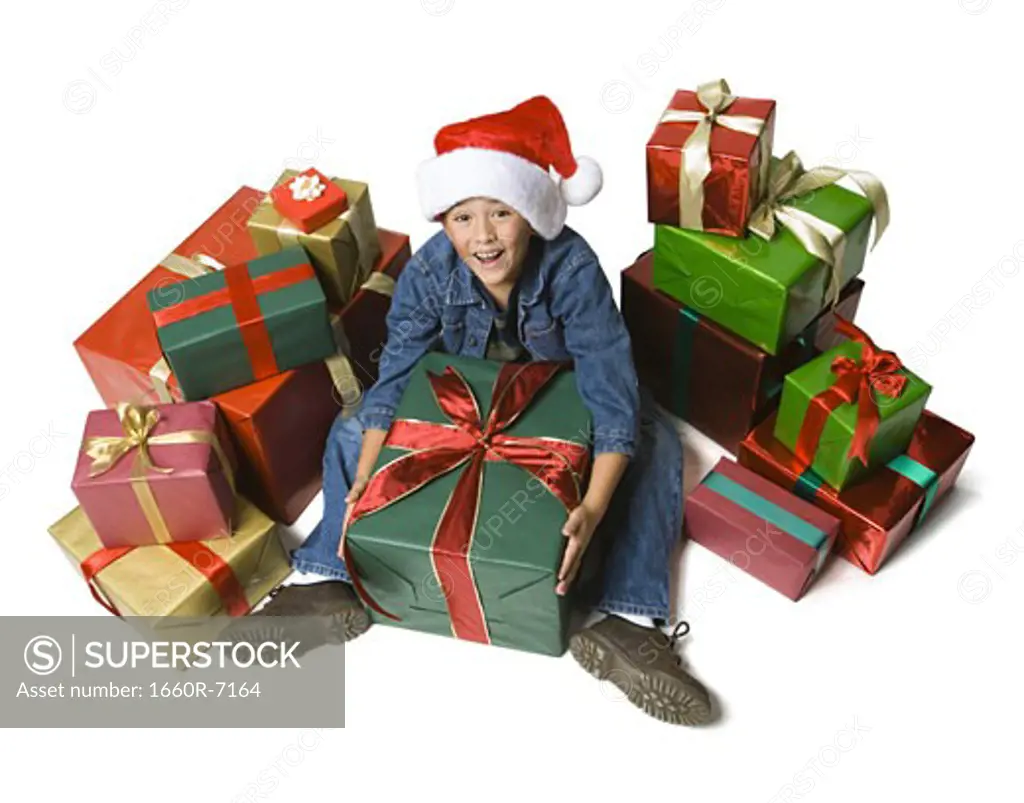 High angle view of a boy sitting on the floor with Christmas presents around him