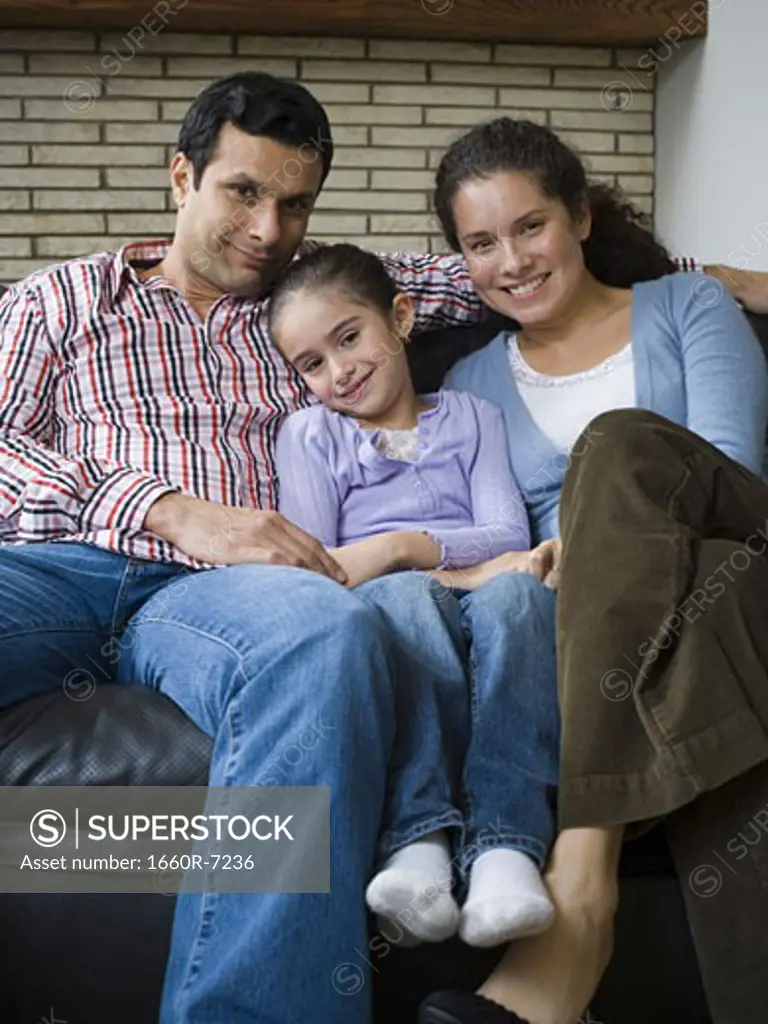 Portrait of parents and their daughter sitting on a couch and smiling