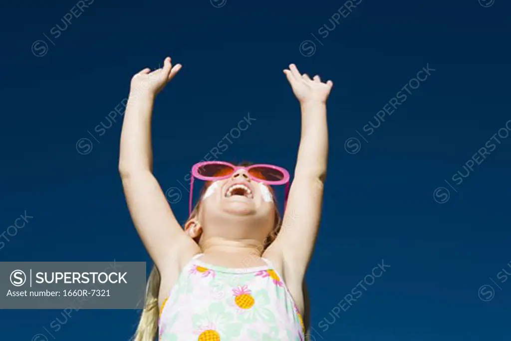 Low angle view of a girl laughing with her arms raised