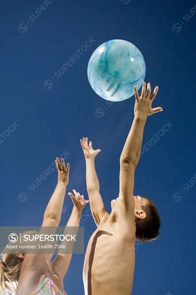Low angle view of a brother and sister playing with a beach ball