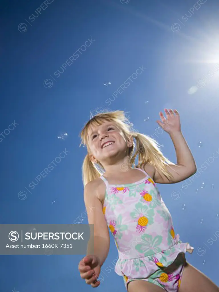 Low angle view of a girl smiling and surrounded by bubbles