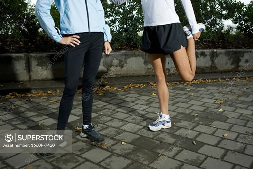 Low section view of two women exercising on a sidewalk