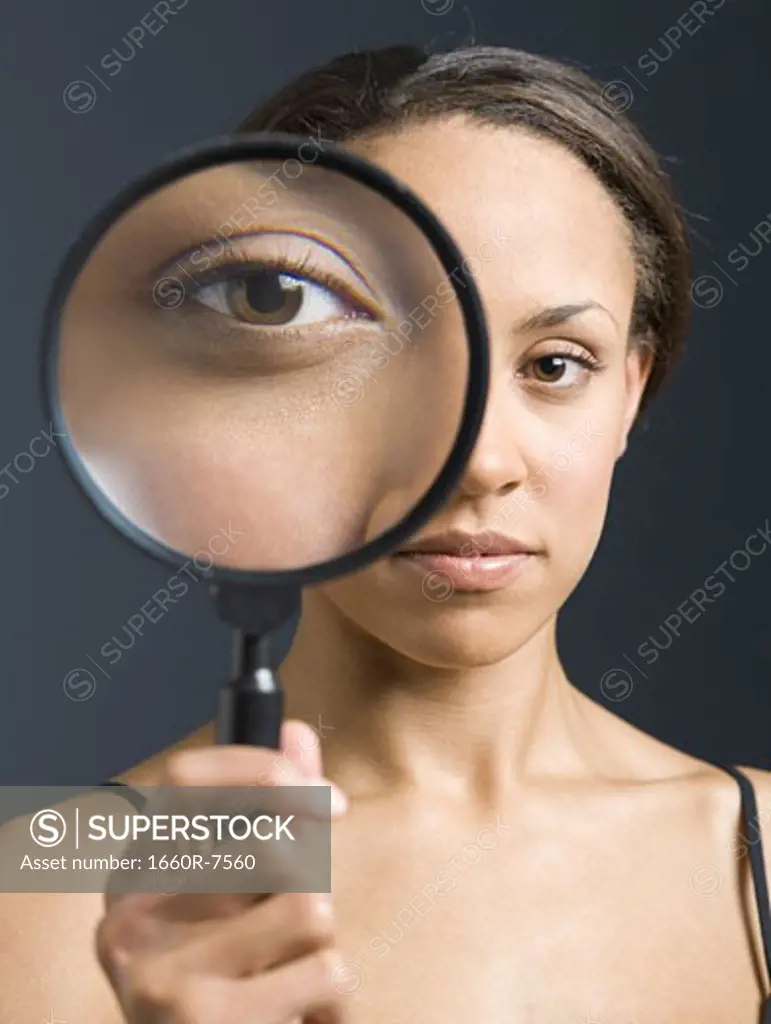 Portrait of a young woman looking through a magnifying glass