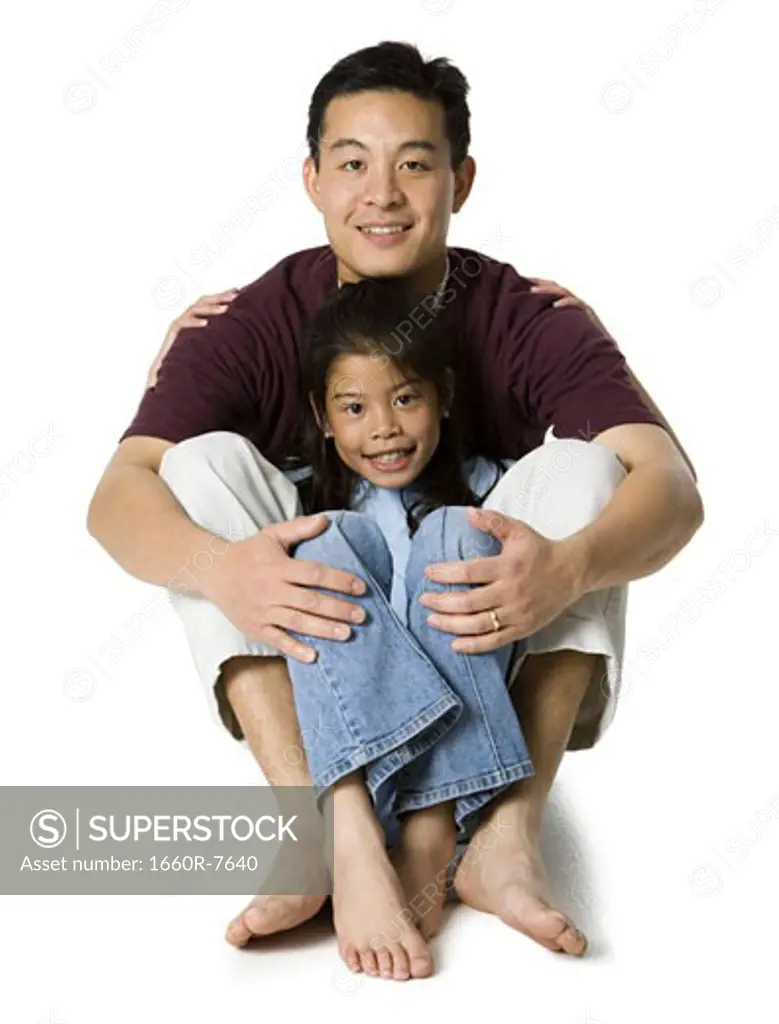 Portrait of a father sitting on the floor with his daughter and smiling