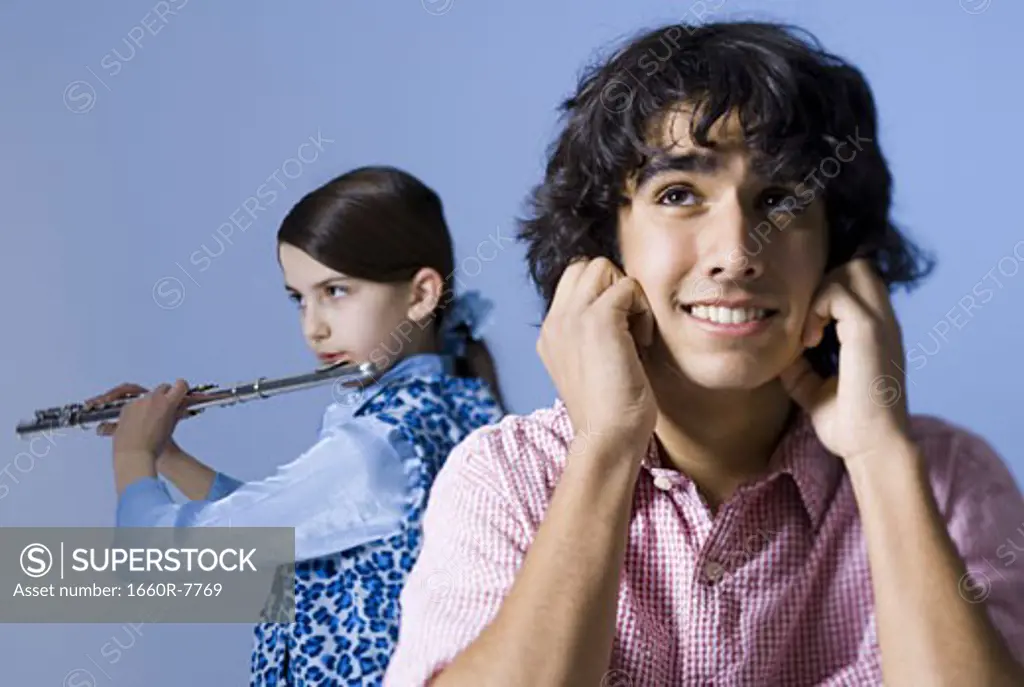 Close-up of a teenage girl playing the flute behind a teenage boy