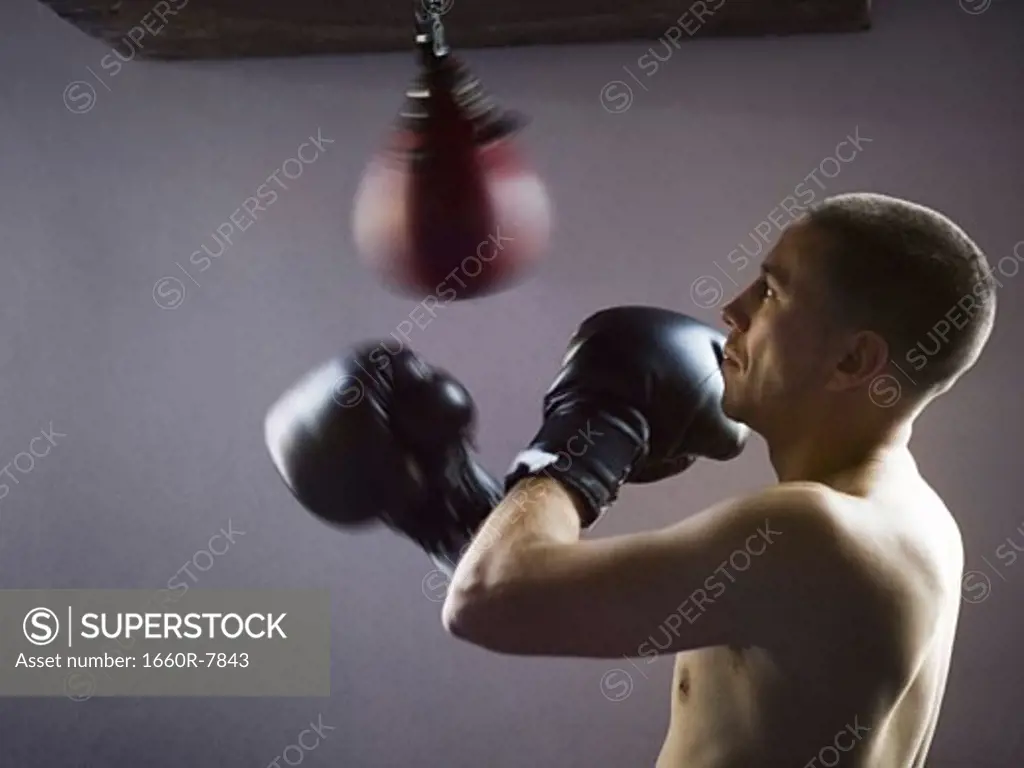 Profile of a young man punching a punching bag