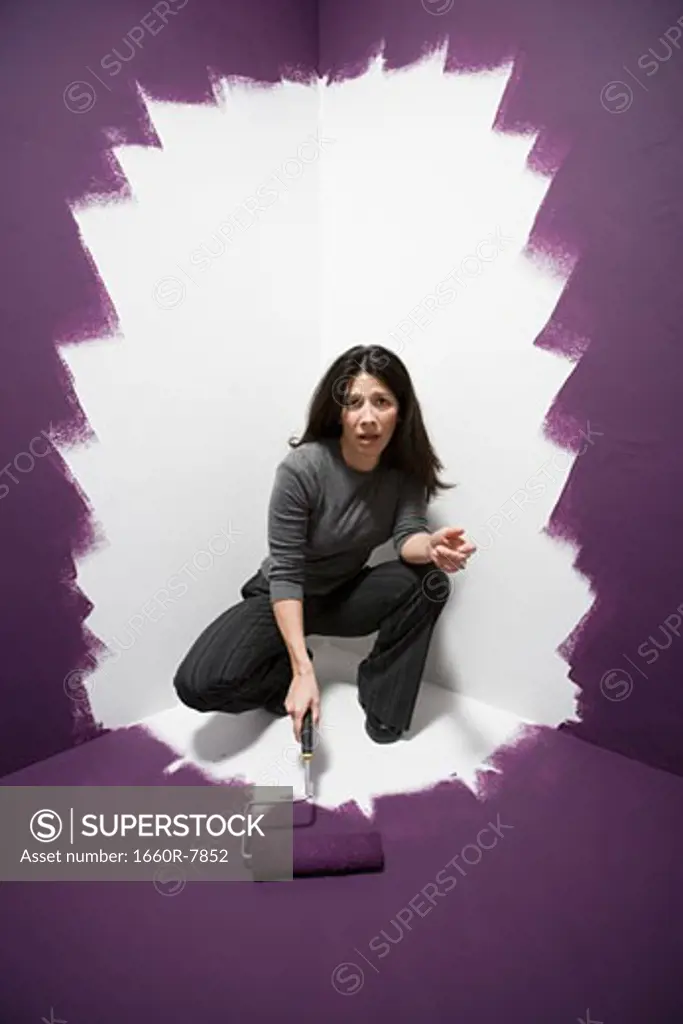 Portrait of a mid adult woman painting herself into a corner