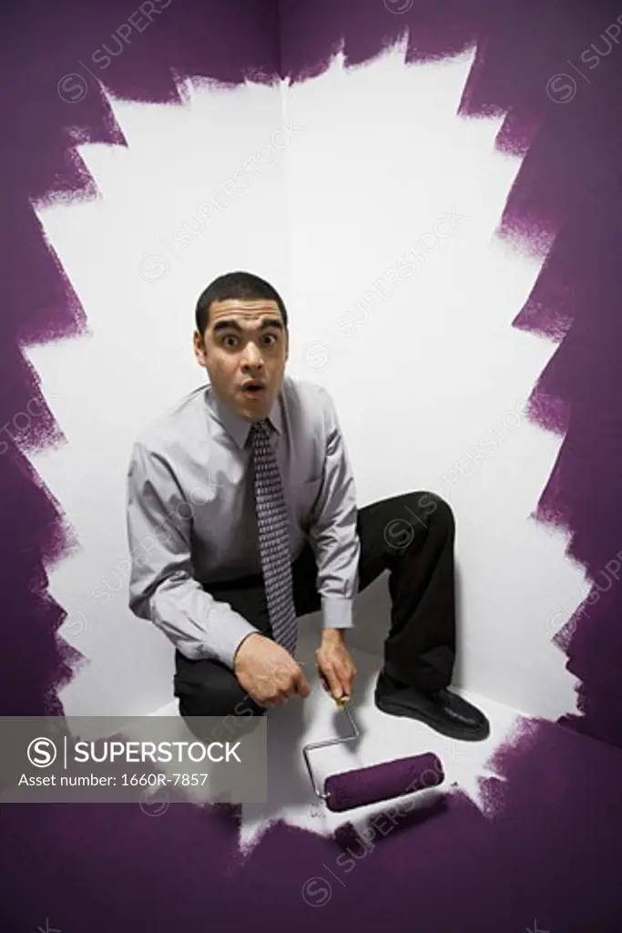 Portrait of a businessman painting himself into a corner