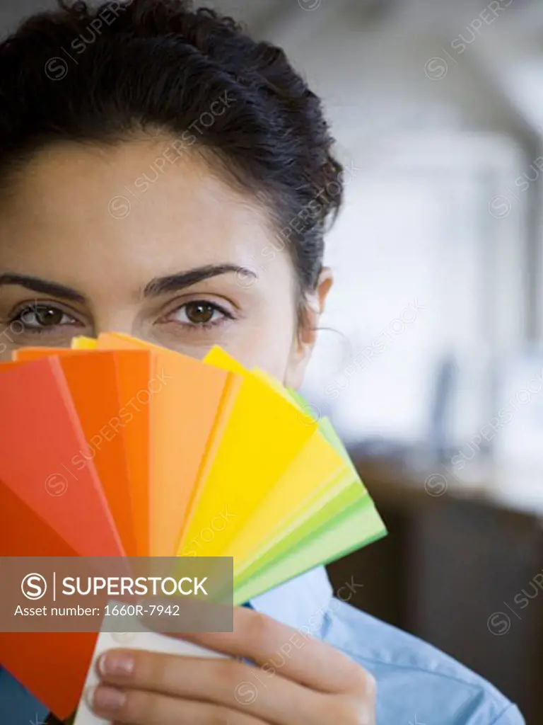Portrait of a young woman holding color swatches in front of her face