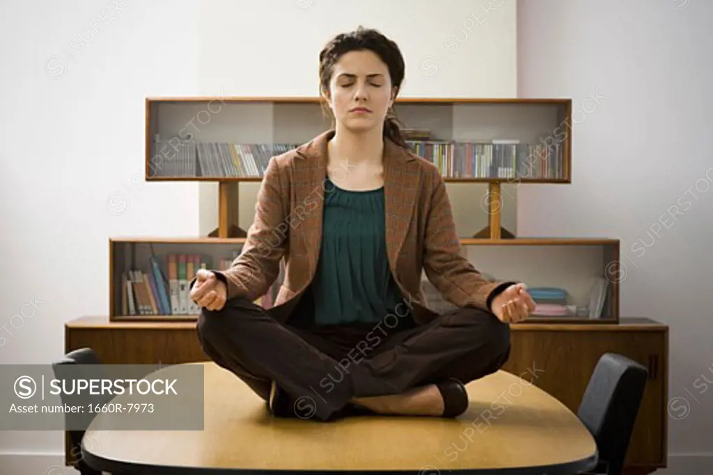 Young woman meditating on a meeting table