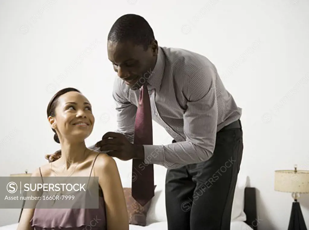 Man putting on a necklace around a woman's neck