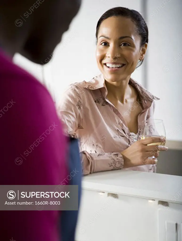 Woman holding a glass of white wine talking to man