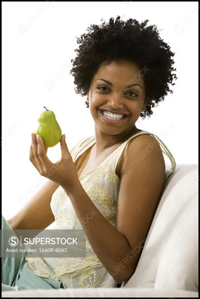 Portrait of a young woman holding a pear