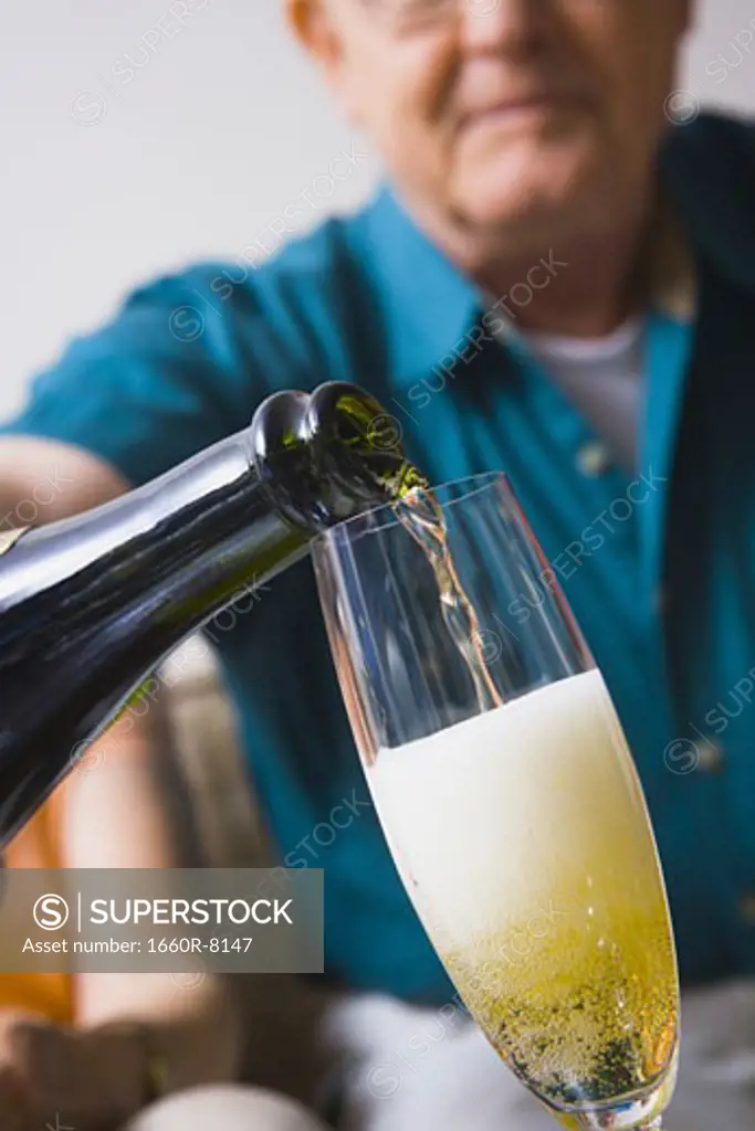 Low angle view of a man's hand pouring champagne into a champagne flute