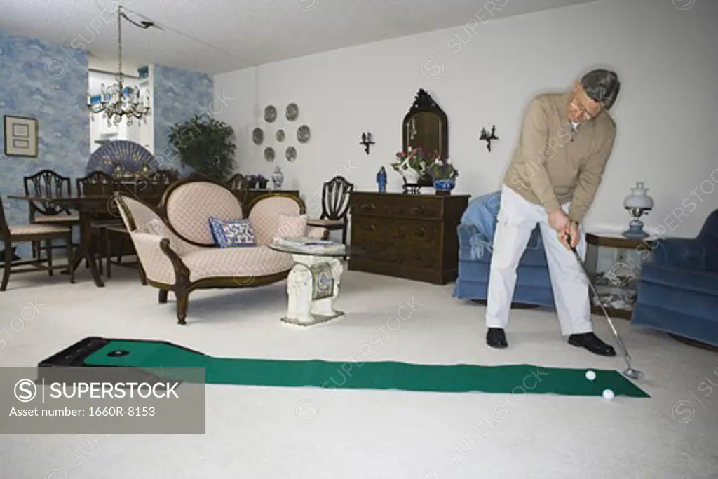 Senior man playing golf in the living room