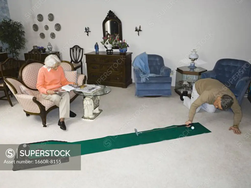 High angle view of a senior man playing golf in the living room