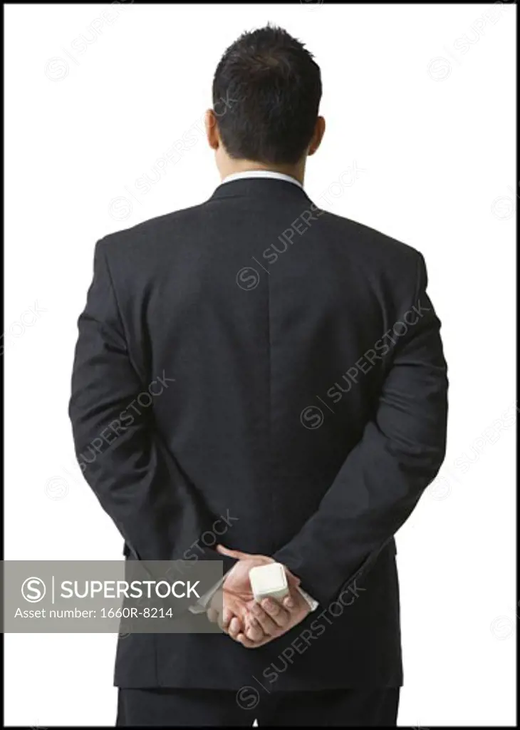 Rear view of a businessman hiding a jewelry box behind his back