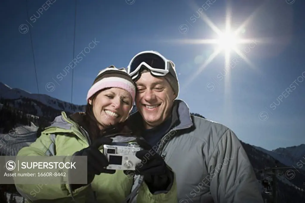 Low angle view of an adult couple looking at a digital camera