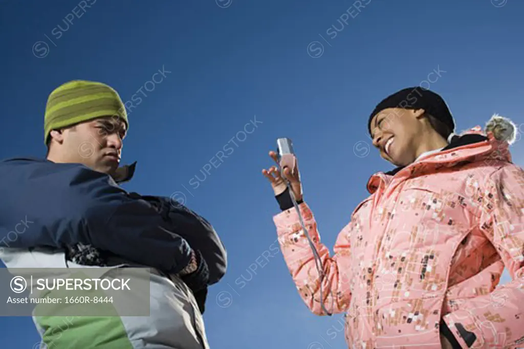 Low angle view of a young woman taking a photograph of an adult man
