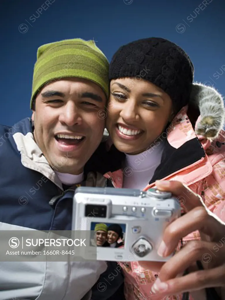 Low angle view of a young woman and an adult man looking at a digital camera