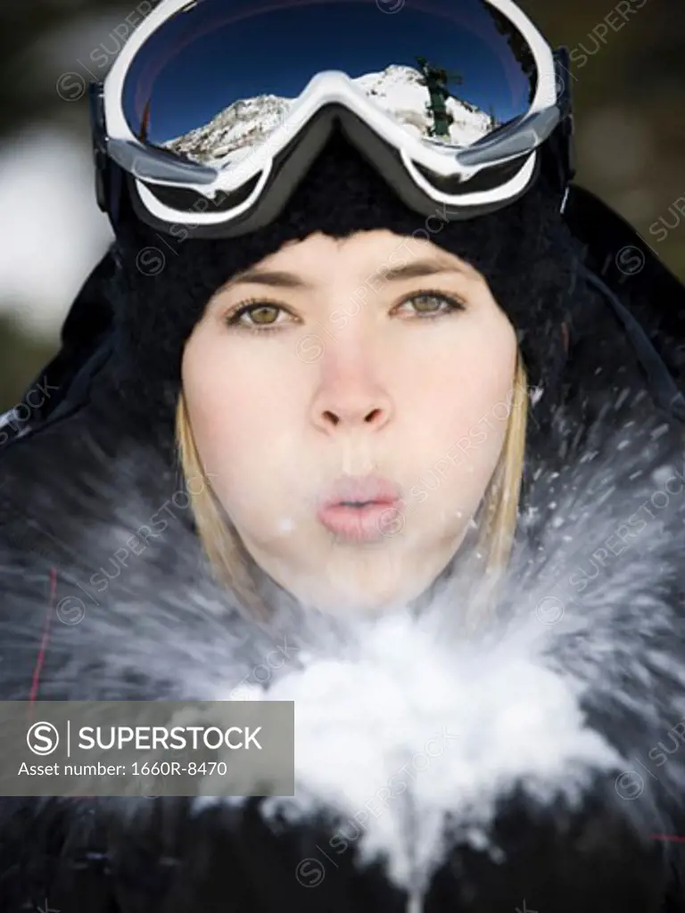 Portrait of a young woman blowing snow