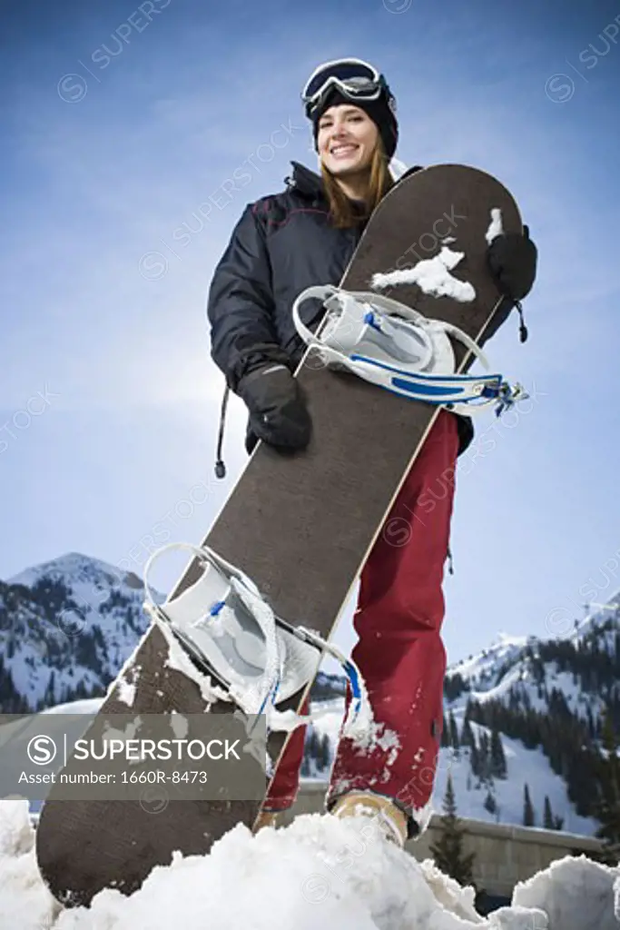 Low angle view of a young woman holding a snowboard