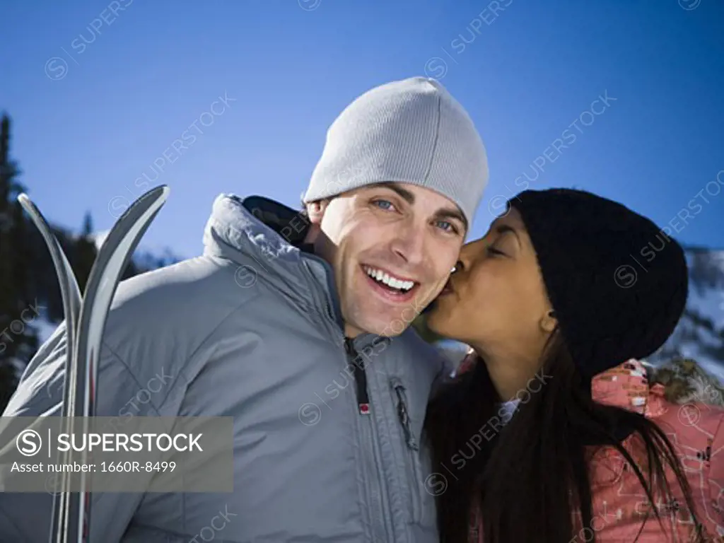 Close-up of a young woman kissing a young man on the cheek