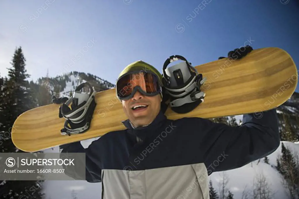 Portrait of an adult man holding a snowboard on his shoulder