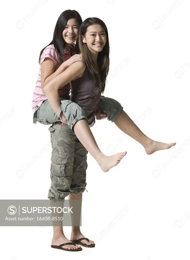Portrait of a teenage girl riding piggyback on her sister