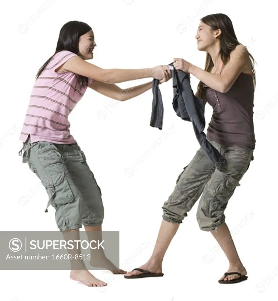 Profile of two teenage girls tugging a top