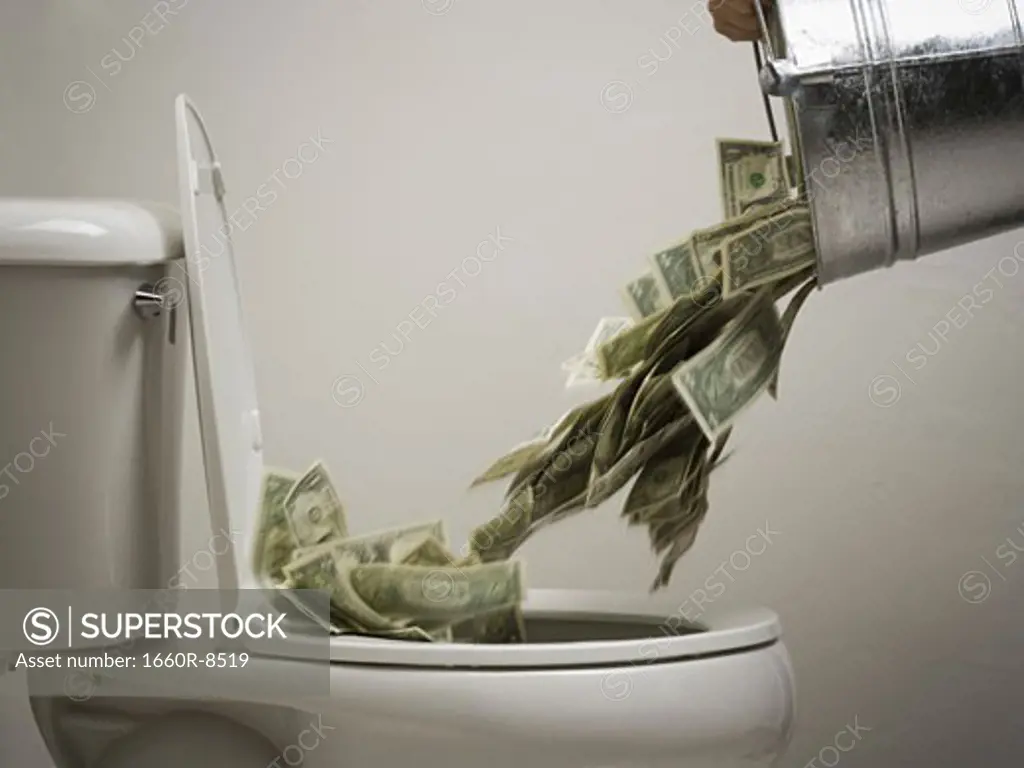 Person dumping money into a toilet bowl