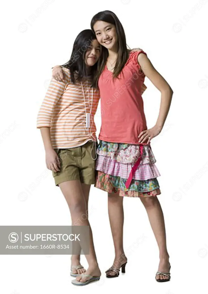 Portrait of a young woman standing with her arm around a teenage girl
