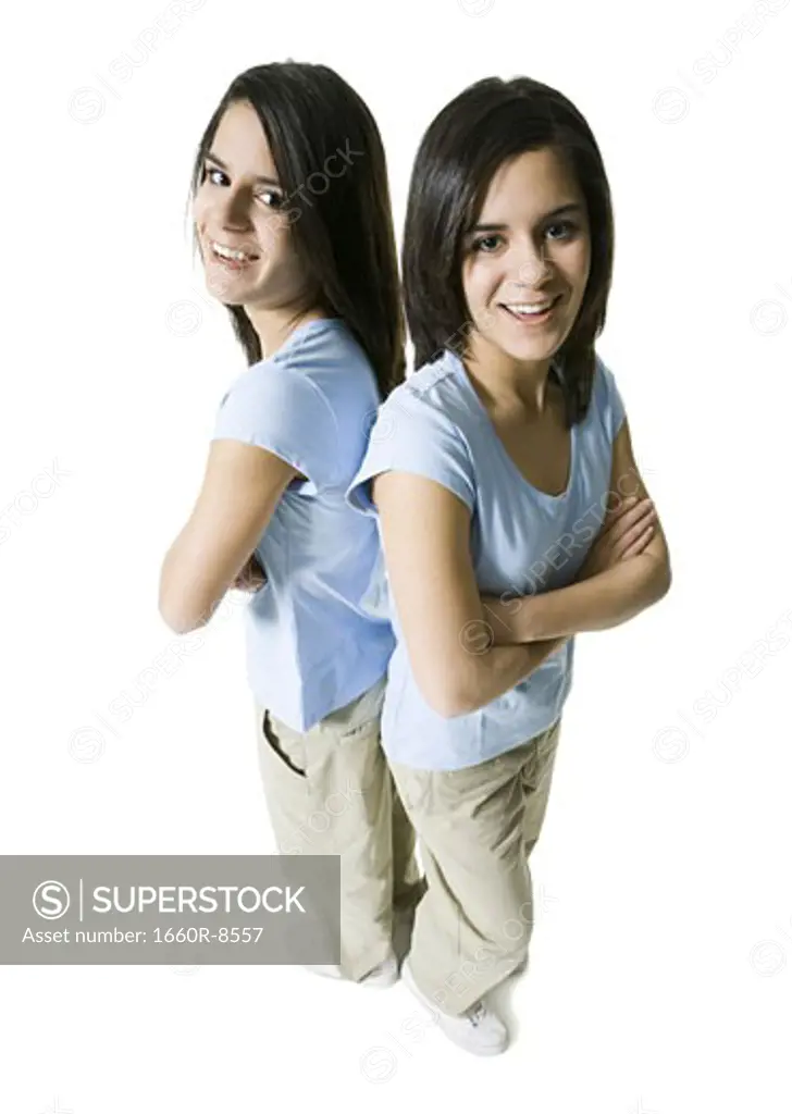 High angle view of two twin teenage girls standing back to back